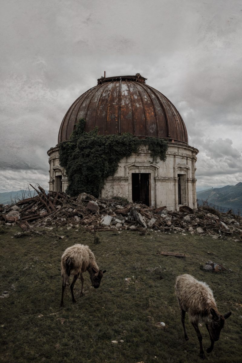 Abandoned Ivy-Covered Observatory Dome and Grazing Sheep in a Ruined Mountain Landscape