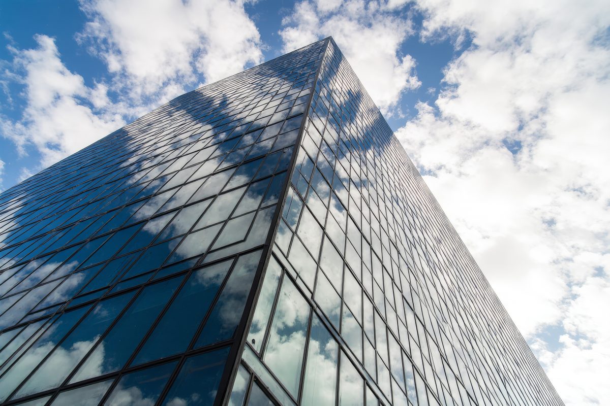 Modern Glass Skyscraper Reflecting Blue Sky and Clouds